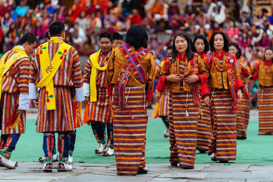 Bhutanese men and women in kira and gho gathered at a festival ground