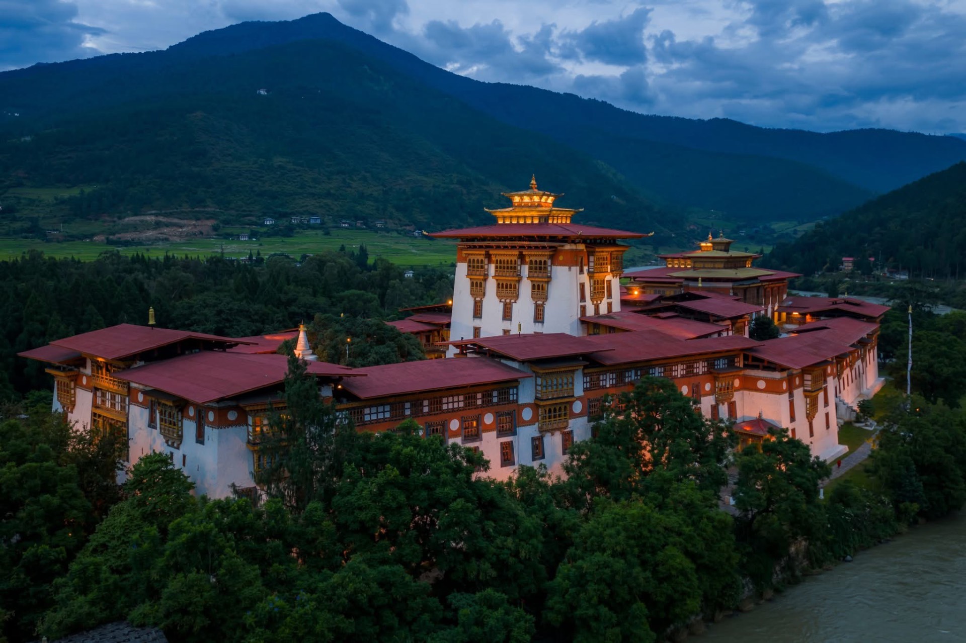 Punakha Dzong at dusk below the forested foothills of the Himalayas