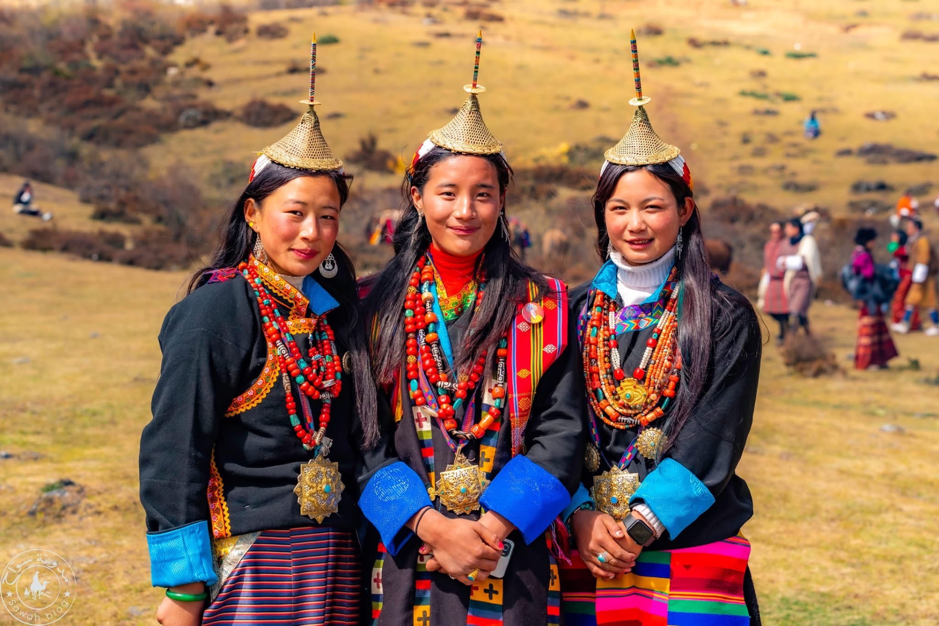 Three Layap women in conical bamboo hats and coral jewellery in a highland field