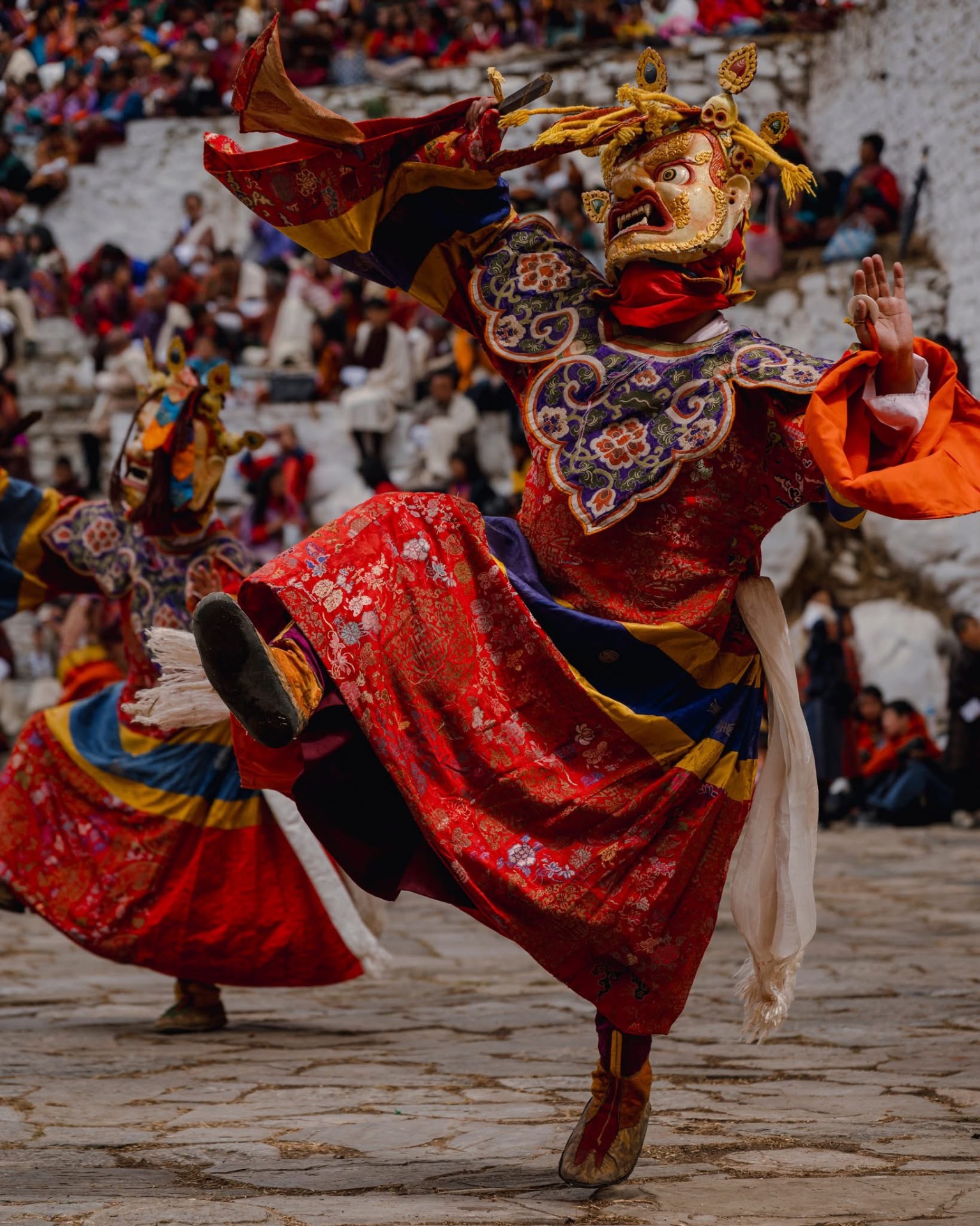A Cham dancer in an ornate mask and brocade robe performing during a tshechu