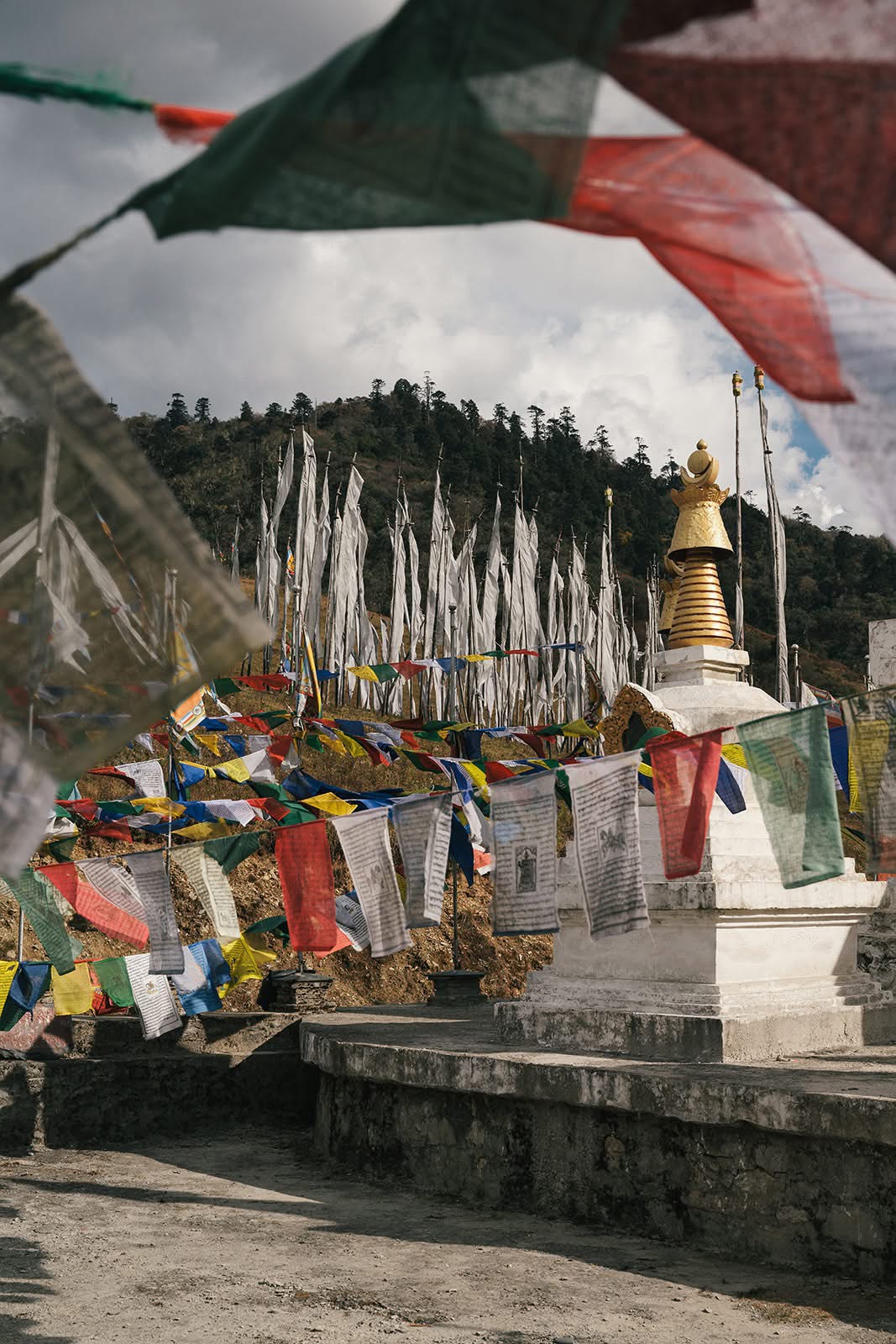 Prayer flags moving in the wind beside a whitewashed chorten on a mountain pass